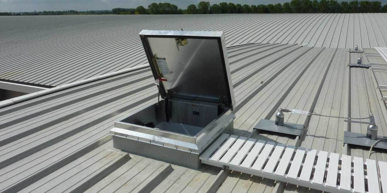 Bilco access hatch with a white walkway on a weatherproofed roof